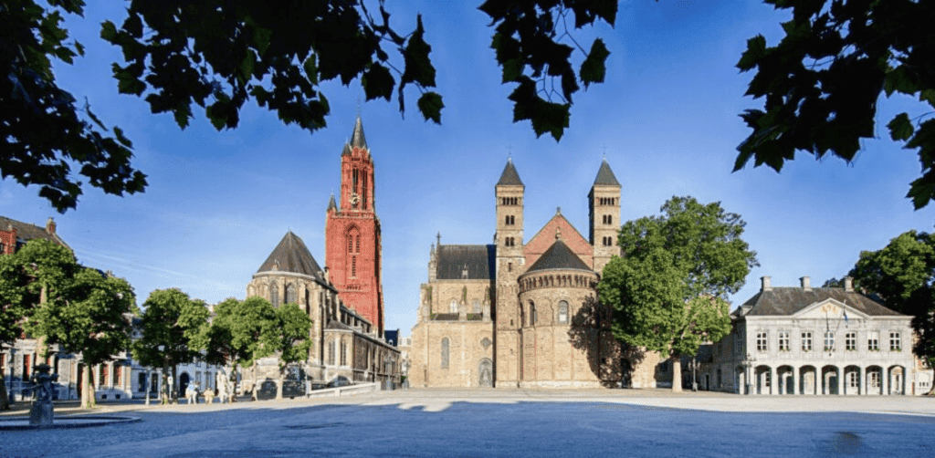 Stadskerk Maastricht en omliggende historische gebouwen onder een heldere blauwe hemel.
